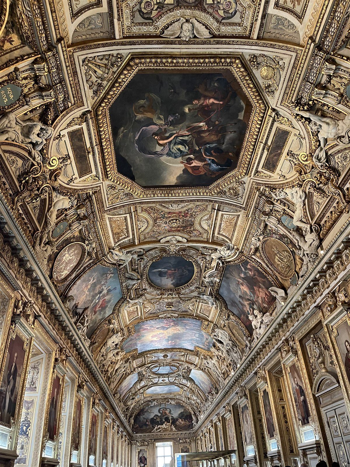 The painted and gilded ceiling of a Louvre gallery, decorated with sculpture and ovals