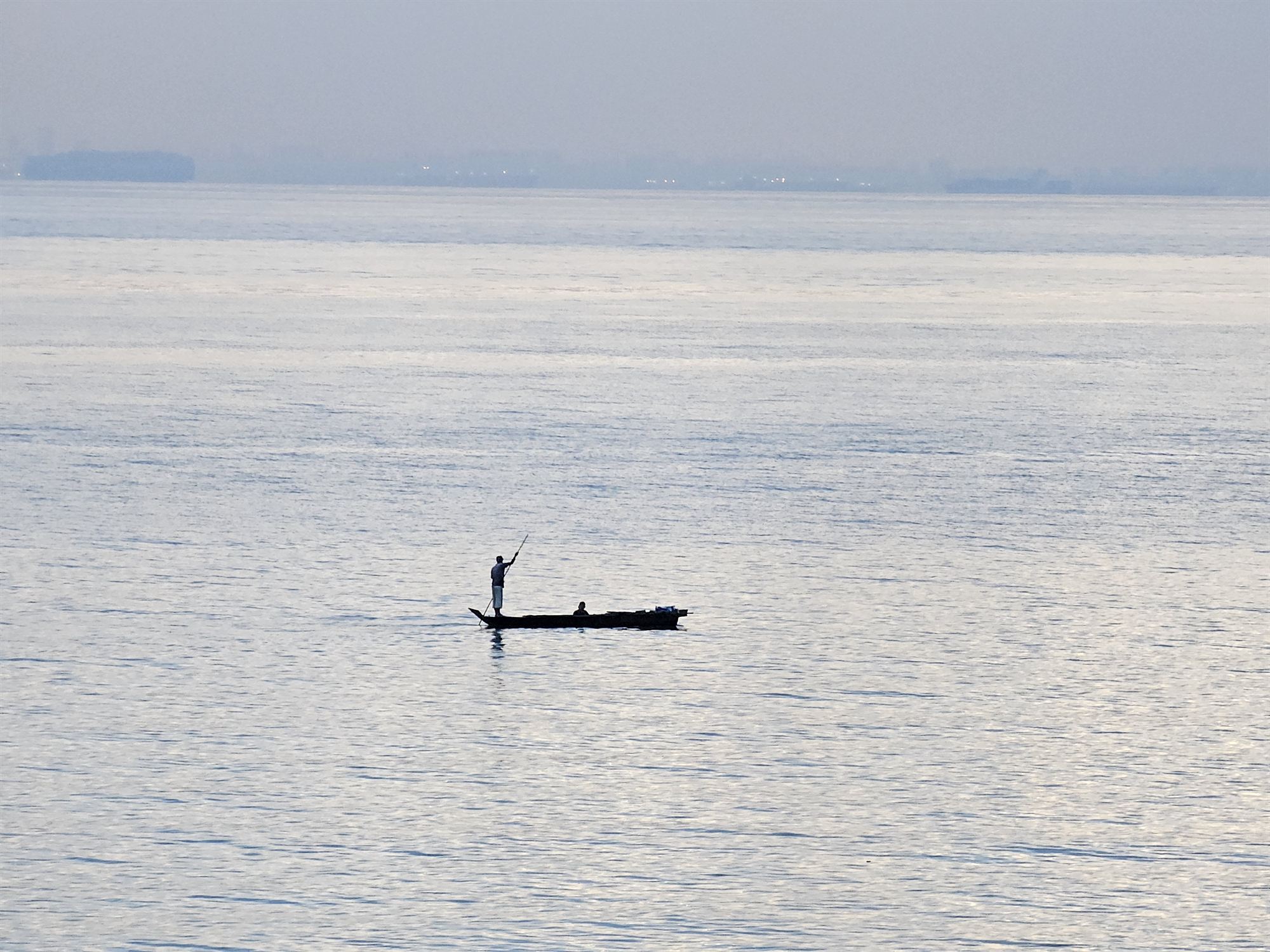 A fisherman in a small boat on the Singapore Strait near Montigo Resort, Batam