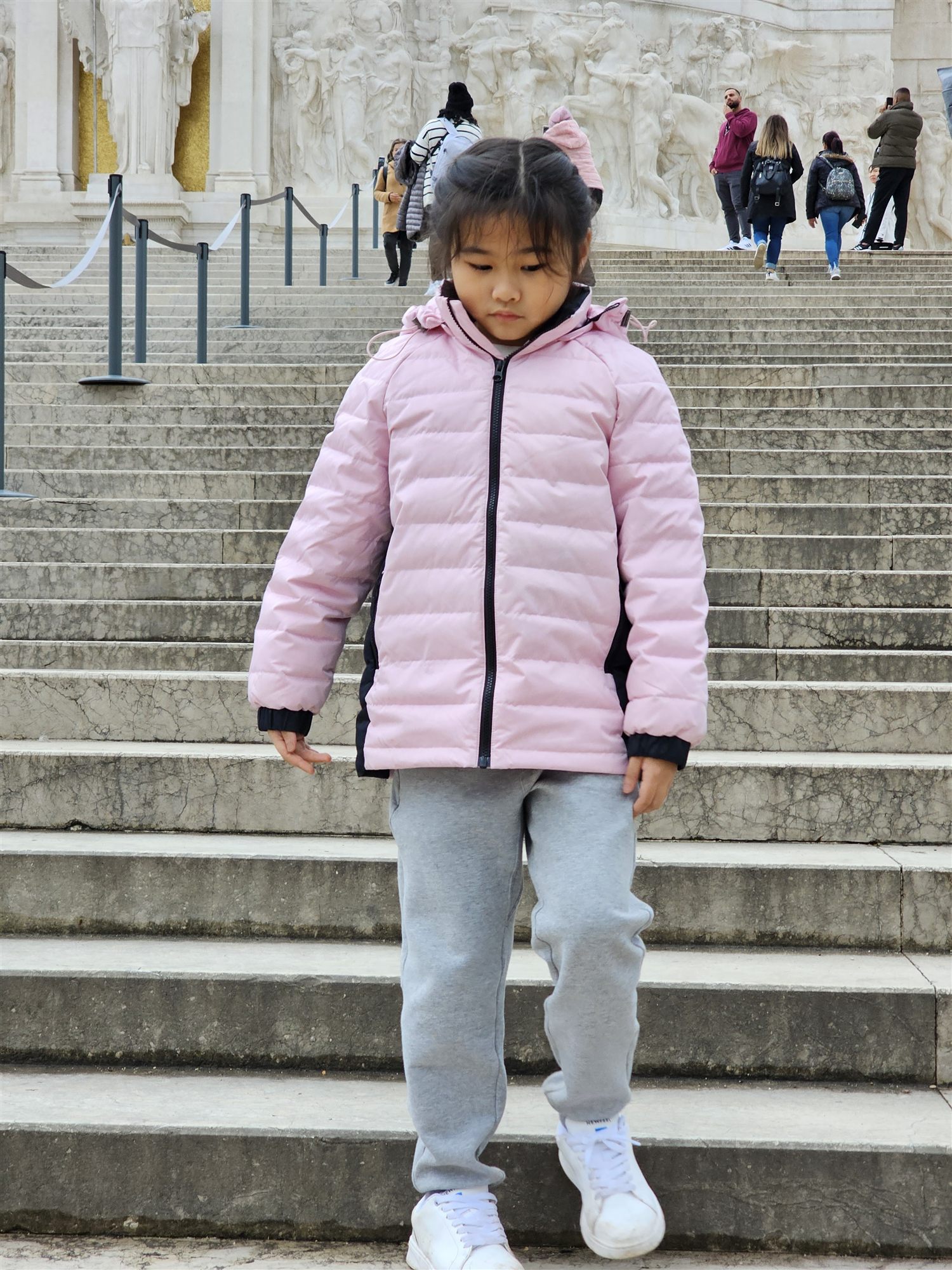 Our daughter standing on the marble steps of the Vittoriano, sculpted reliefs behind her