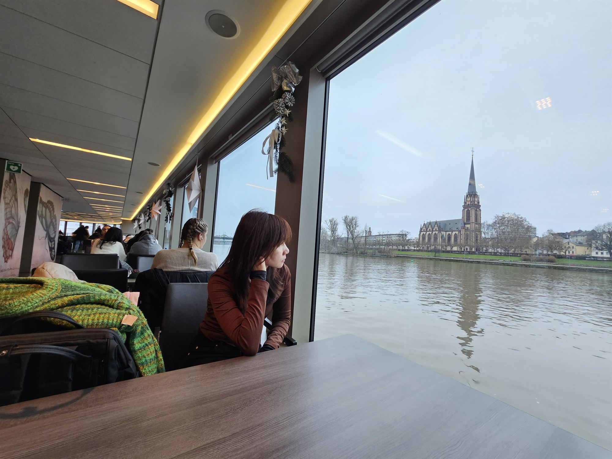 Looking out the cruise boat window at the Dreikönigskirche spire across the Main River