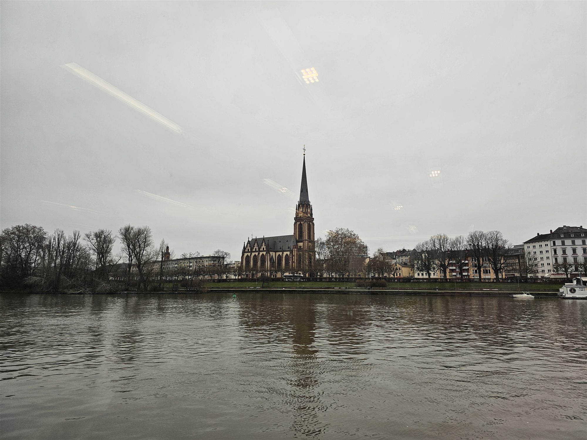 Dreikönigskirche's spire across the Main River, reflected in the water