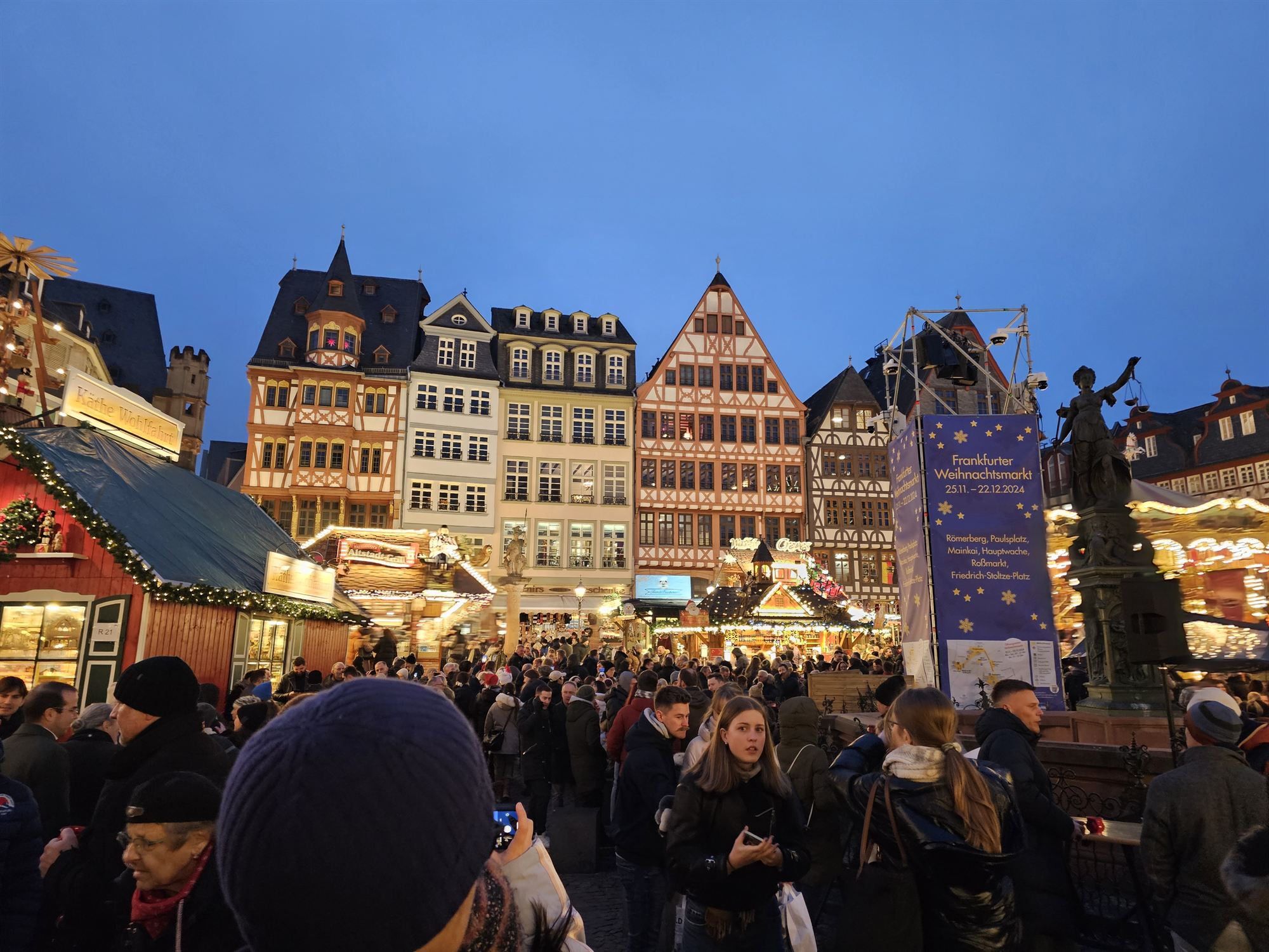 Römerberg square at dusk, half-timbered houses strung with the Frankfurter Weihnachtsmarkt banner