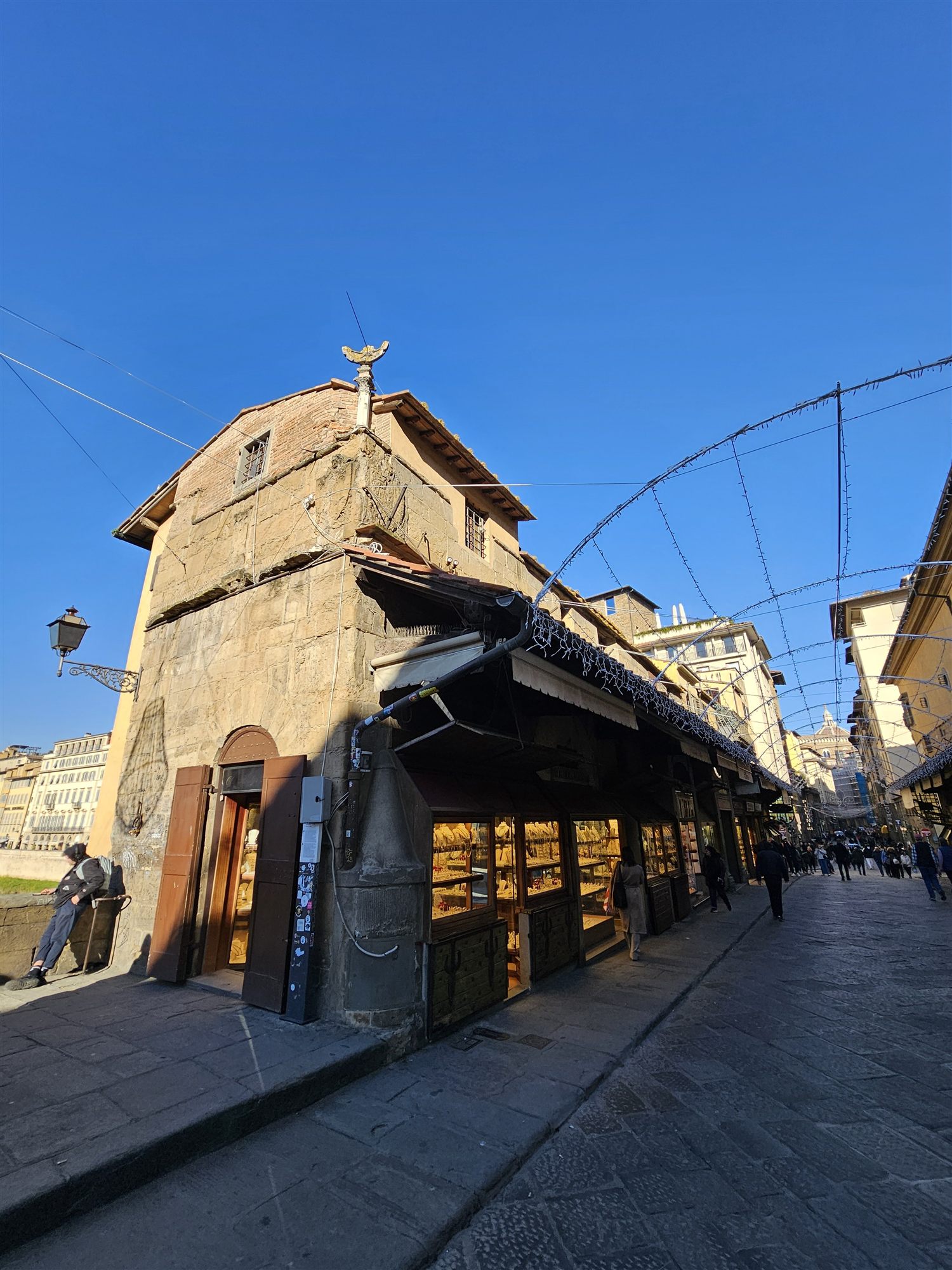 The jewellers' shops built along the Ponte Vecchio, their windows lit in the sunshine