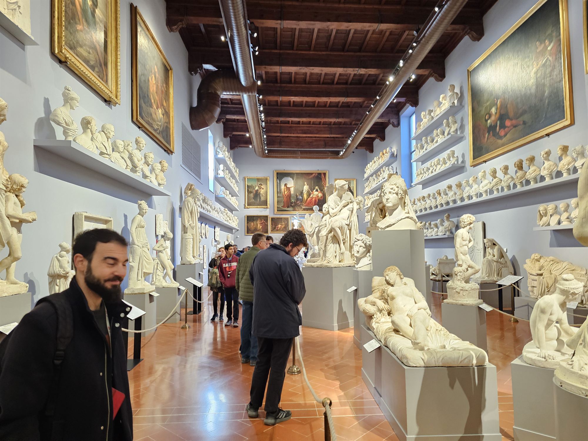 A gallery corridor lined with classical plaster busts and paintings in Florence