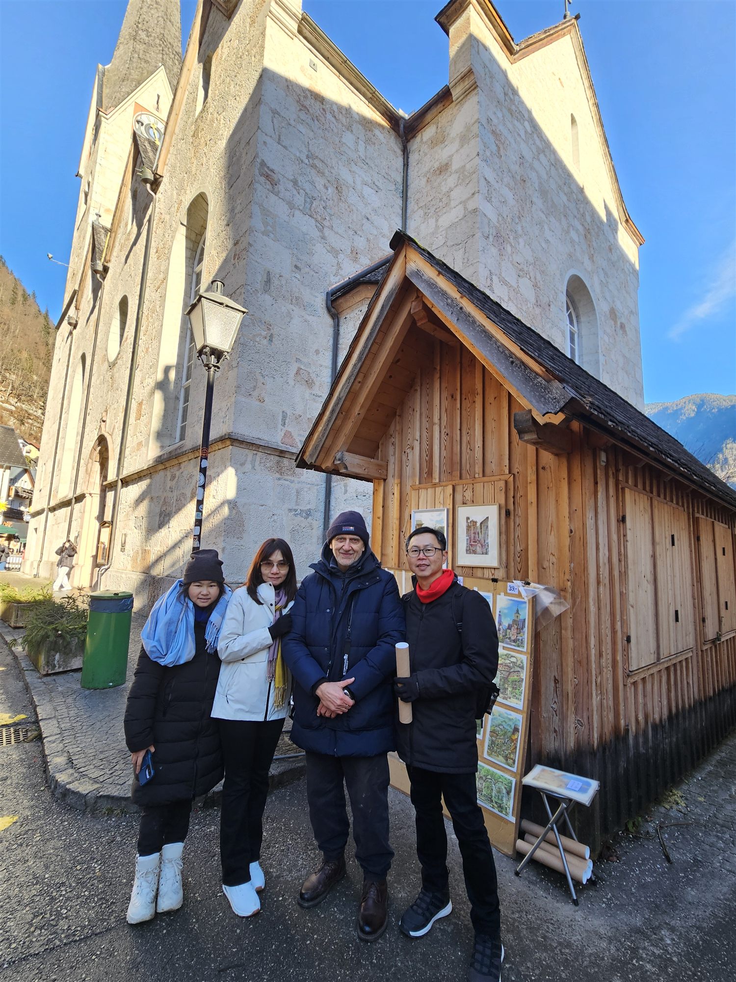 Family with a local artist and his watercolour paintings of Hallstatt, beside the parish church