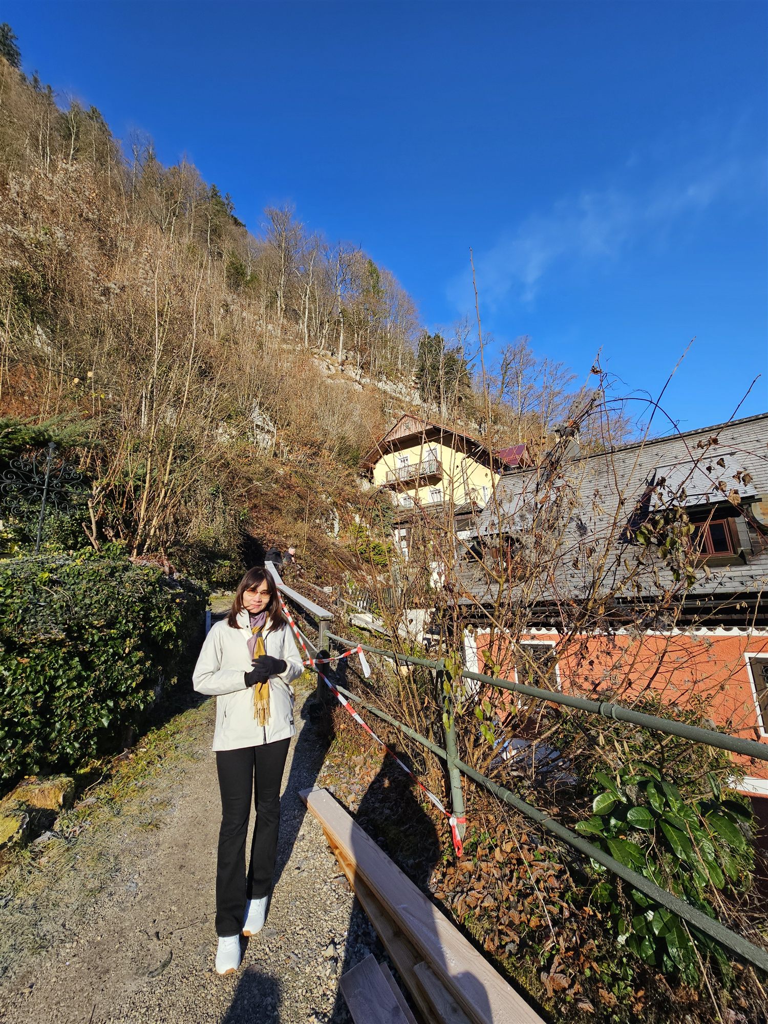 Woman walking a hillside path above Hallstatt, past a taped-off section