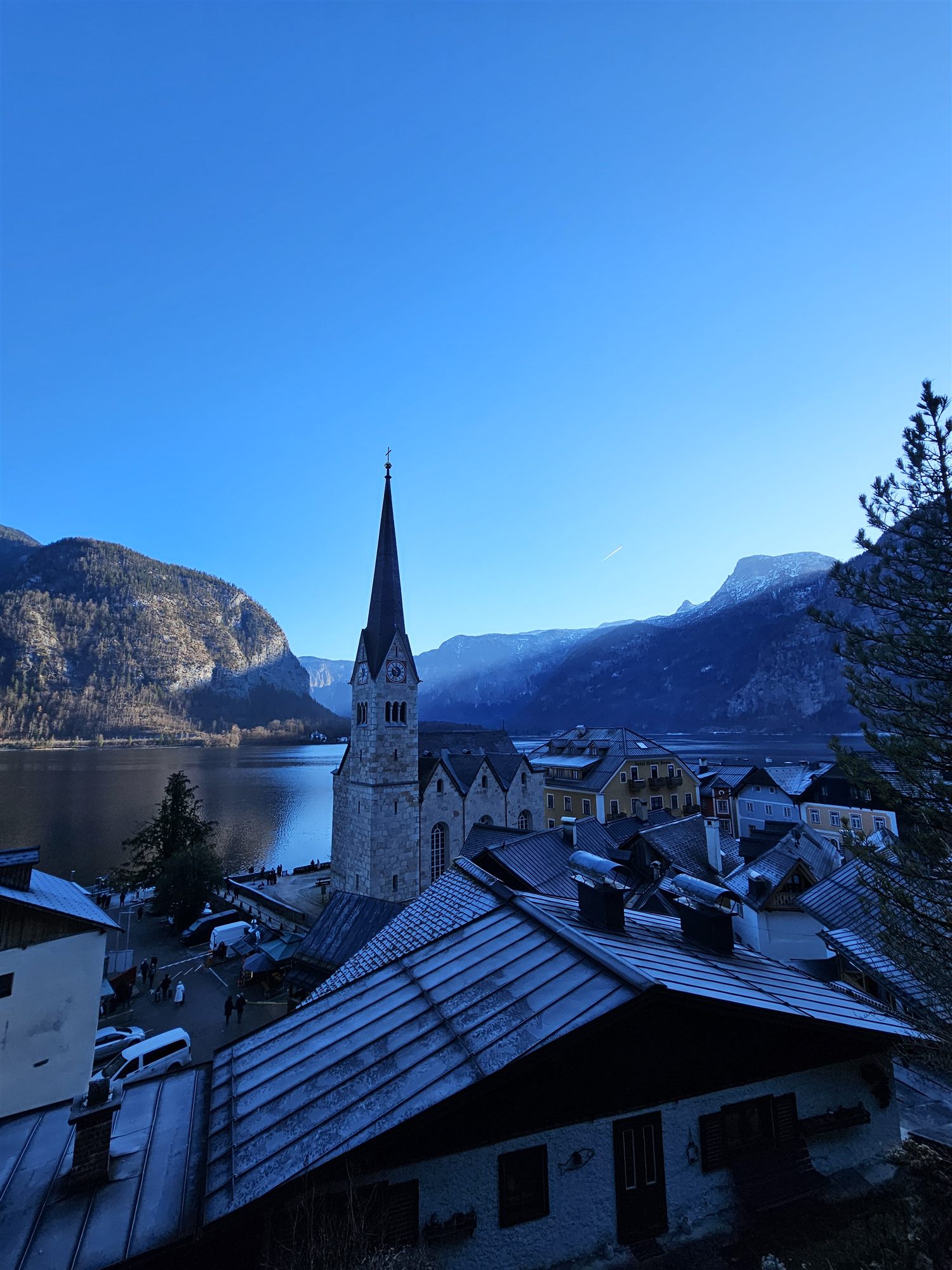 Hallstatt's church and rooftops still in blue morning shadow, seen from above
