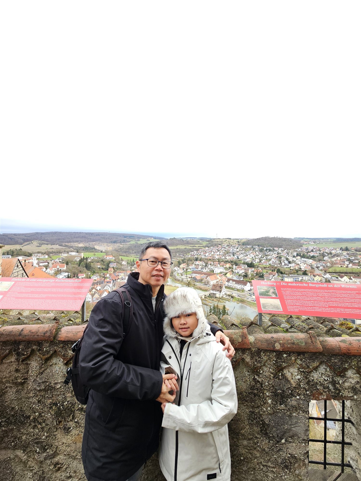 Father and daughter on the castle viewpoint above Harburg, the village and valley spread out below