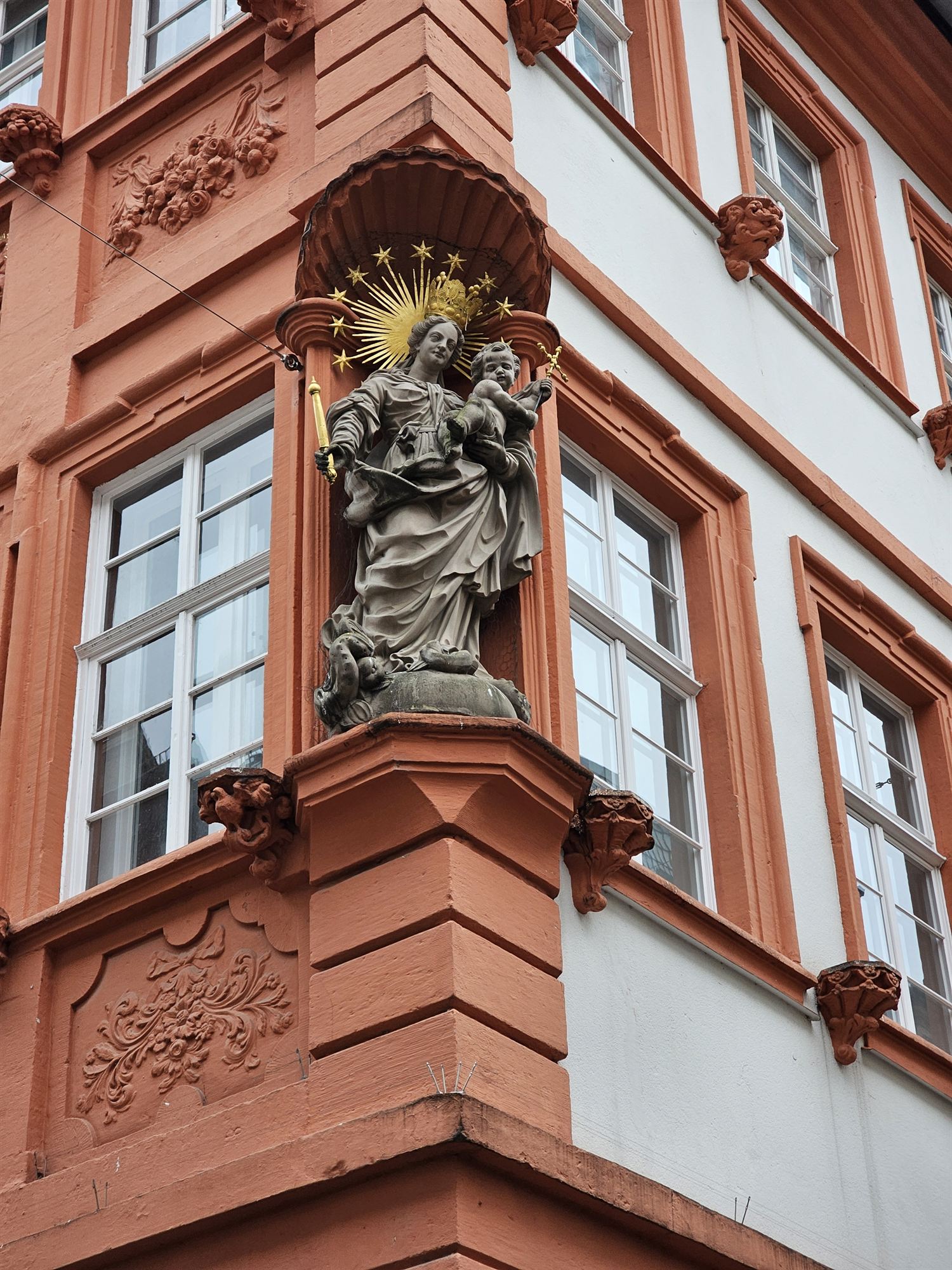 A gilded Madonna and child statue on the corner of a Baroque building in Heidelberg's old town
