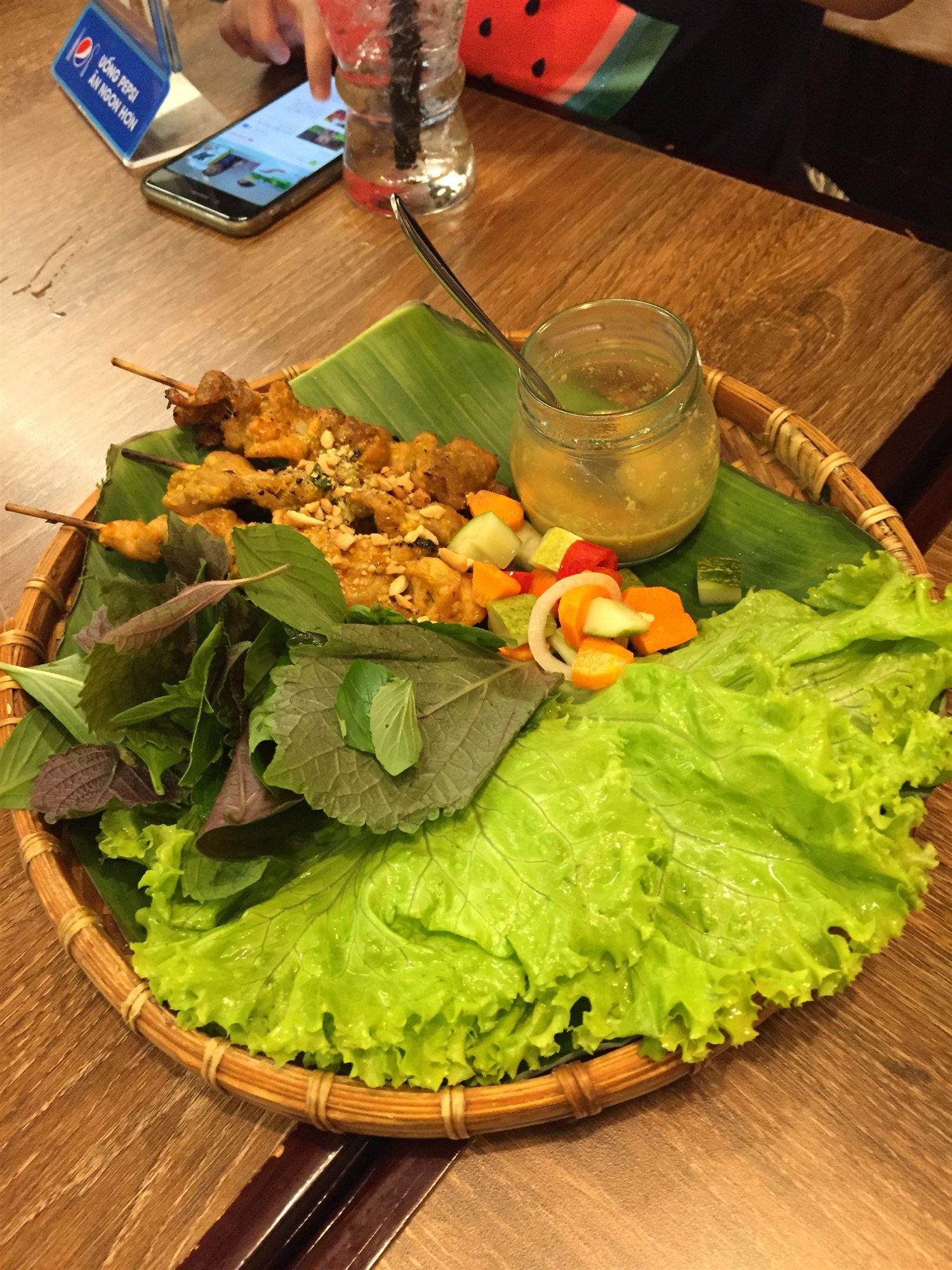 Grilled satay skewers served with fresh herbs, lettuce and dipping sauce