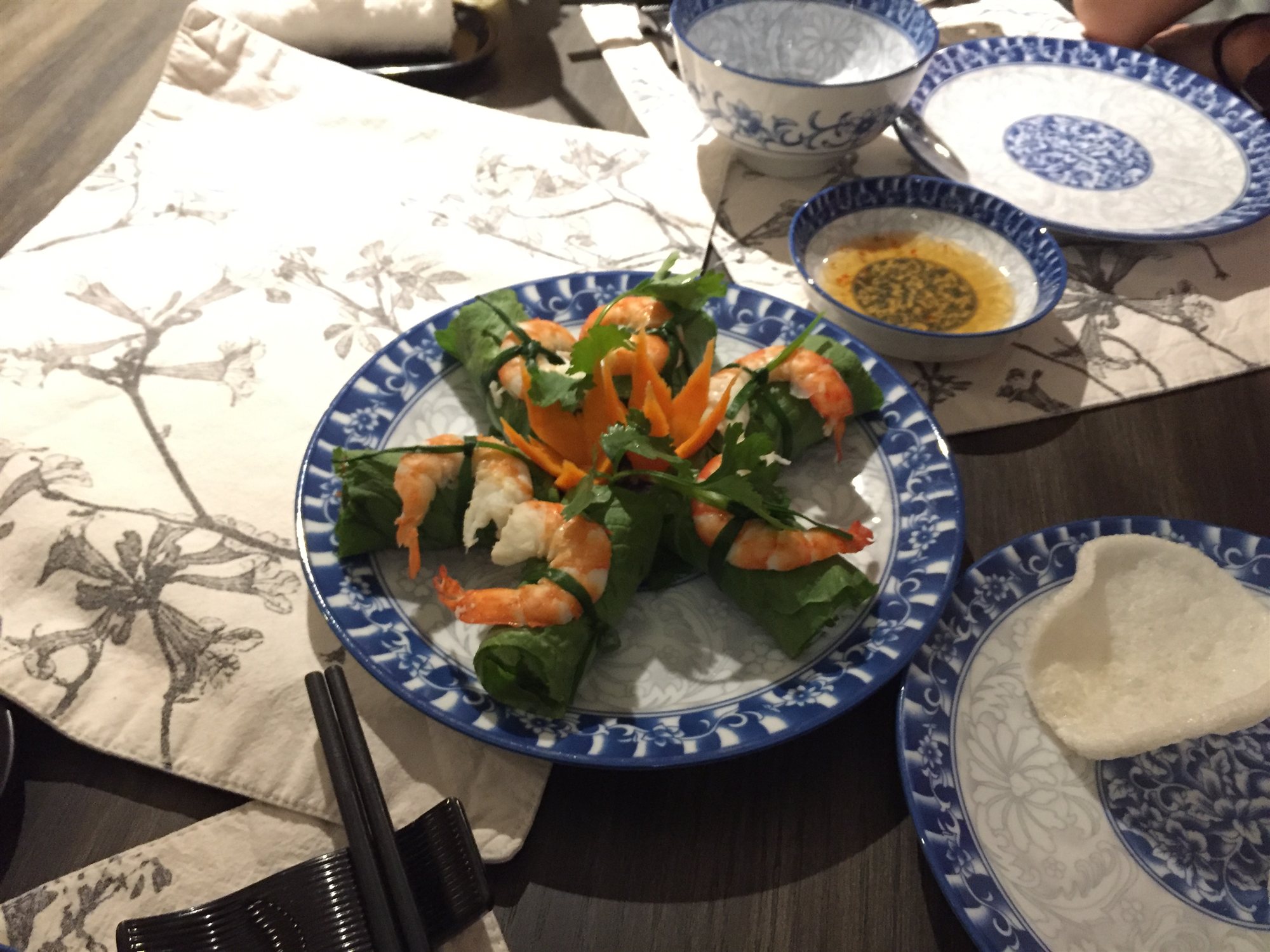 Fresh shrimp rolls wrapped in betel leaf, plated with carrot garnish