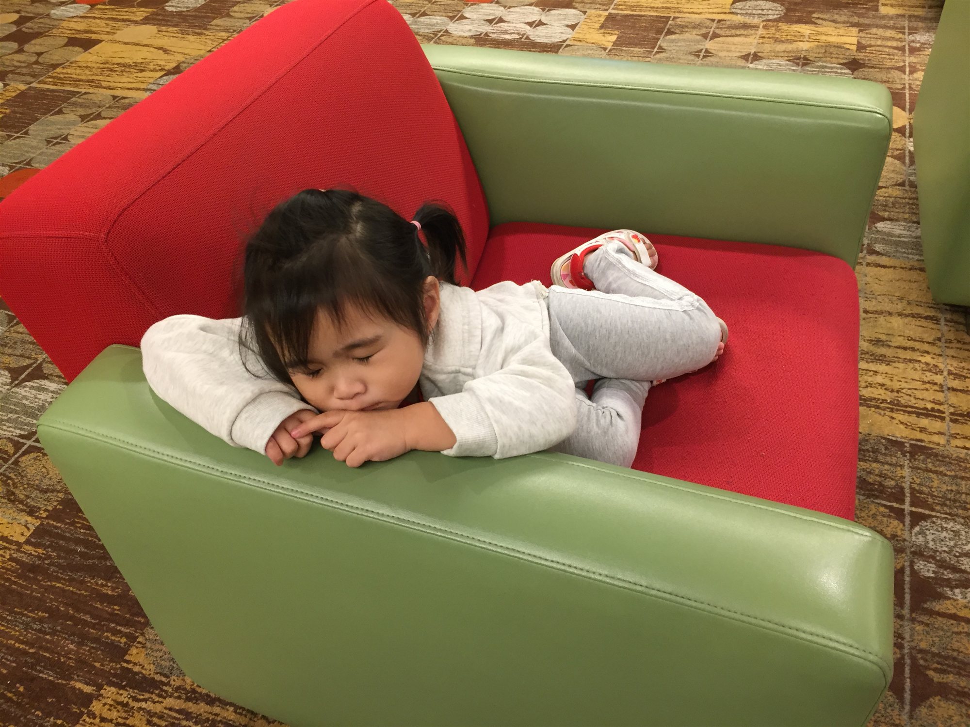 Our daughter resting on a lobby couch after a long day of exploring