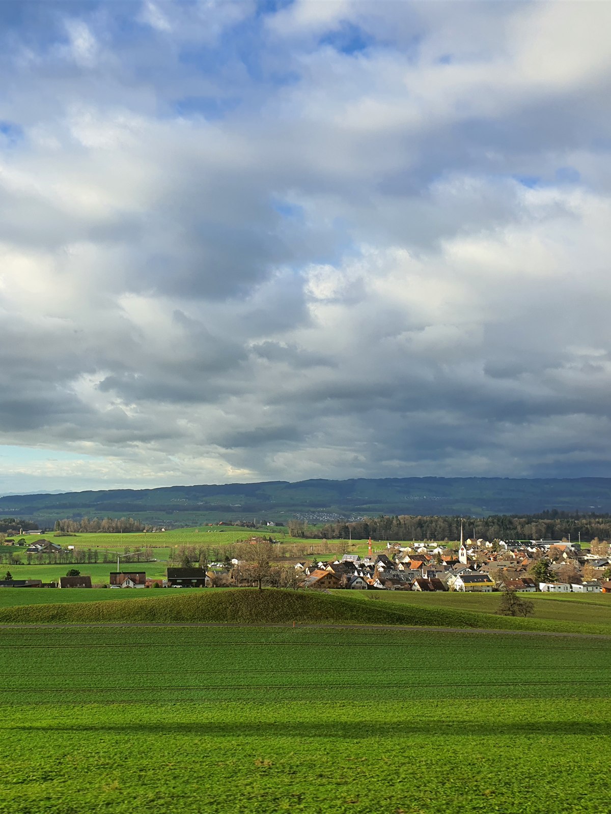 Green fields and a village church seen from the coach window on the way to Lucerne