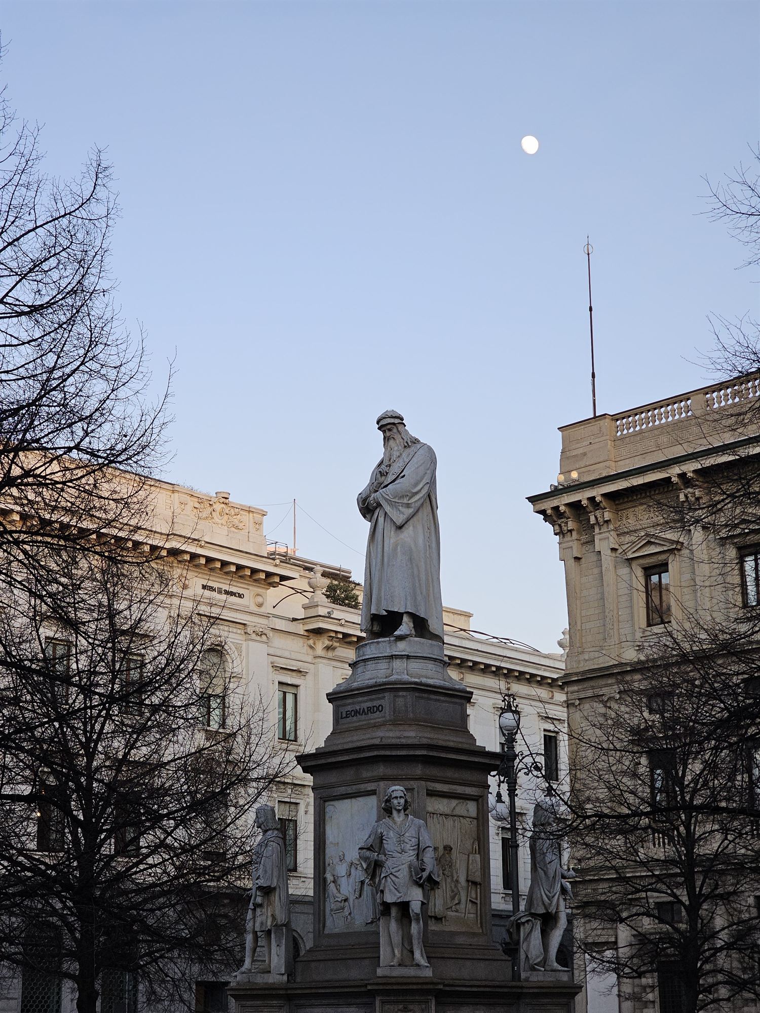 The Leonardo da Vinci statue at Piazza della Scala, Milan, with the moon overhead