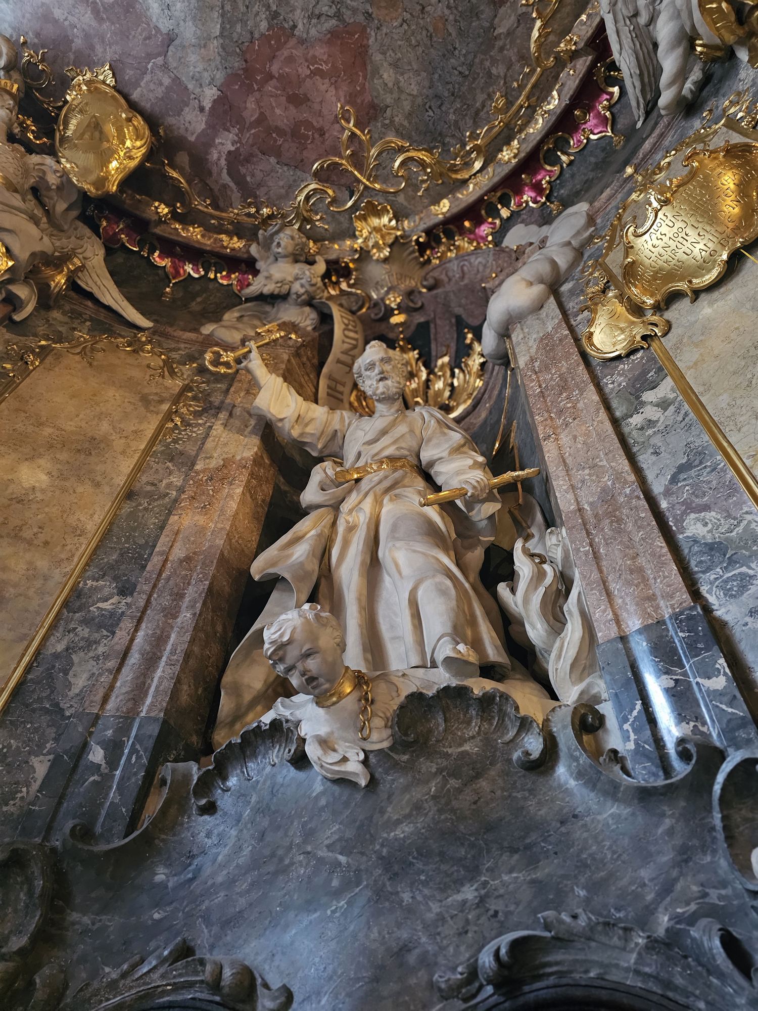 A gilded statue in a shell-shaped niche inside Asamkirche, Munich
