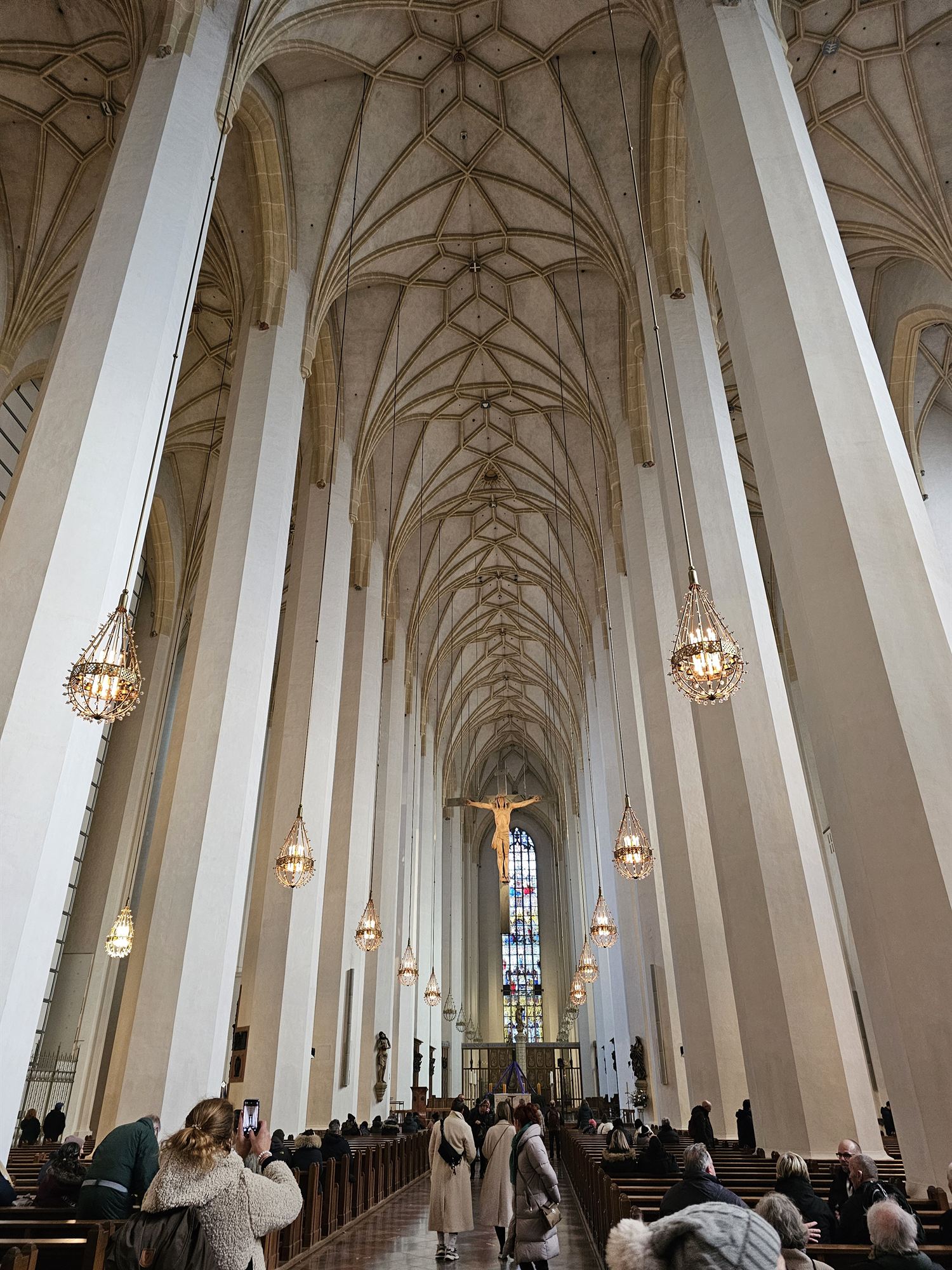 Inside Frauenkirche, Munich, a soaring gothic vaulted ceiling and a crucifix at the altar