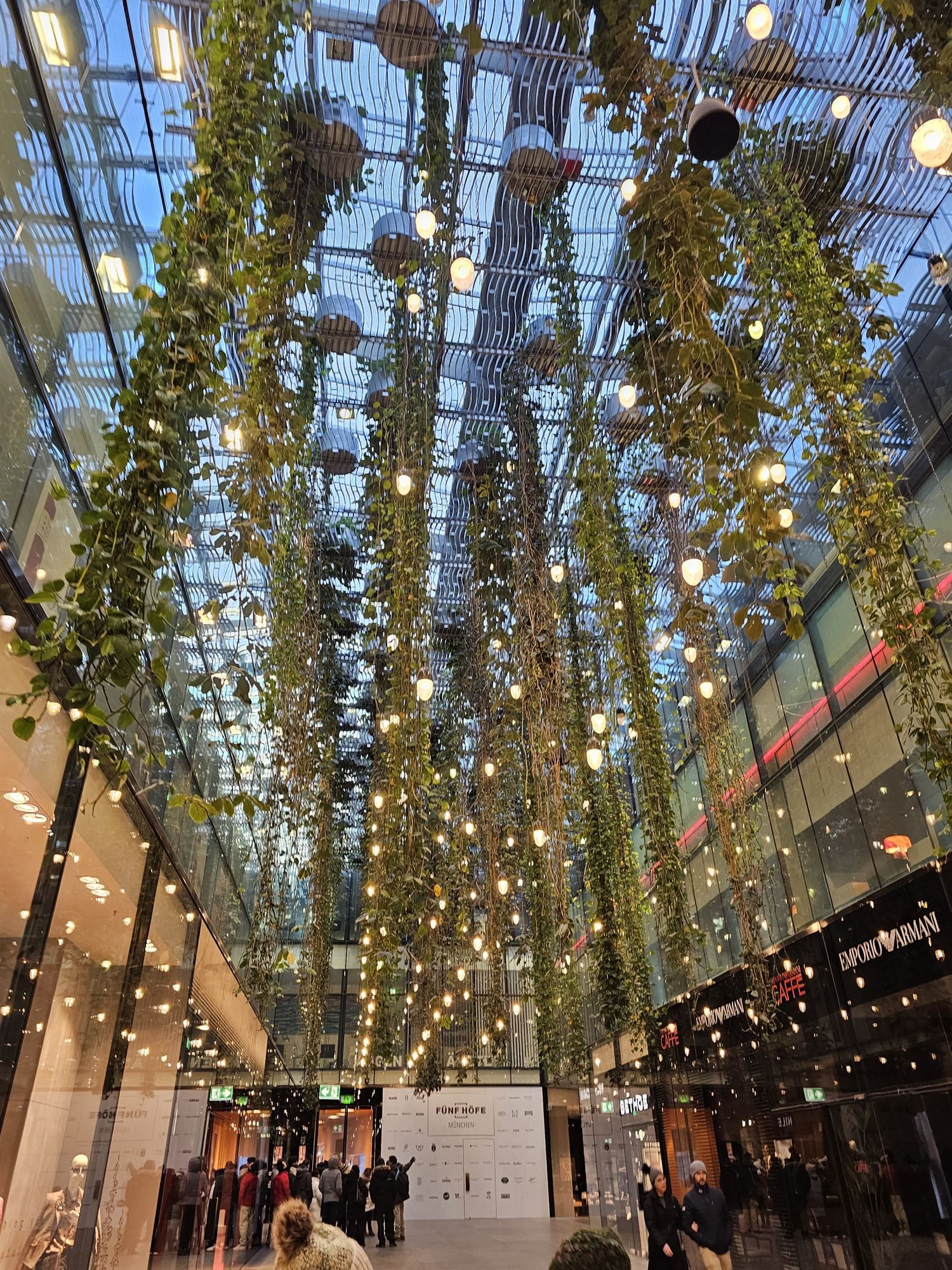 Hanging vines and string lights inside the Fünf Höfe atrium, Munich
