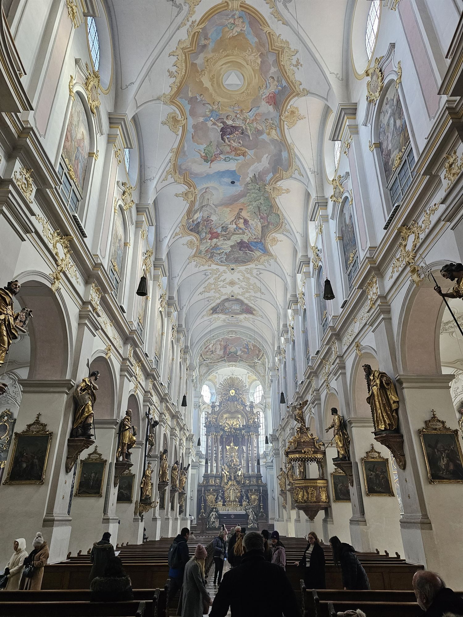 Looking down the nave inside St. Peter's Church, Munich, gilded altars and a painted vaulted ceiling