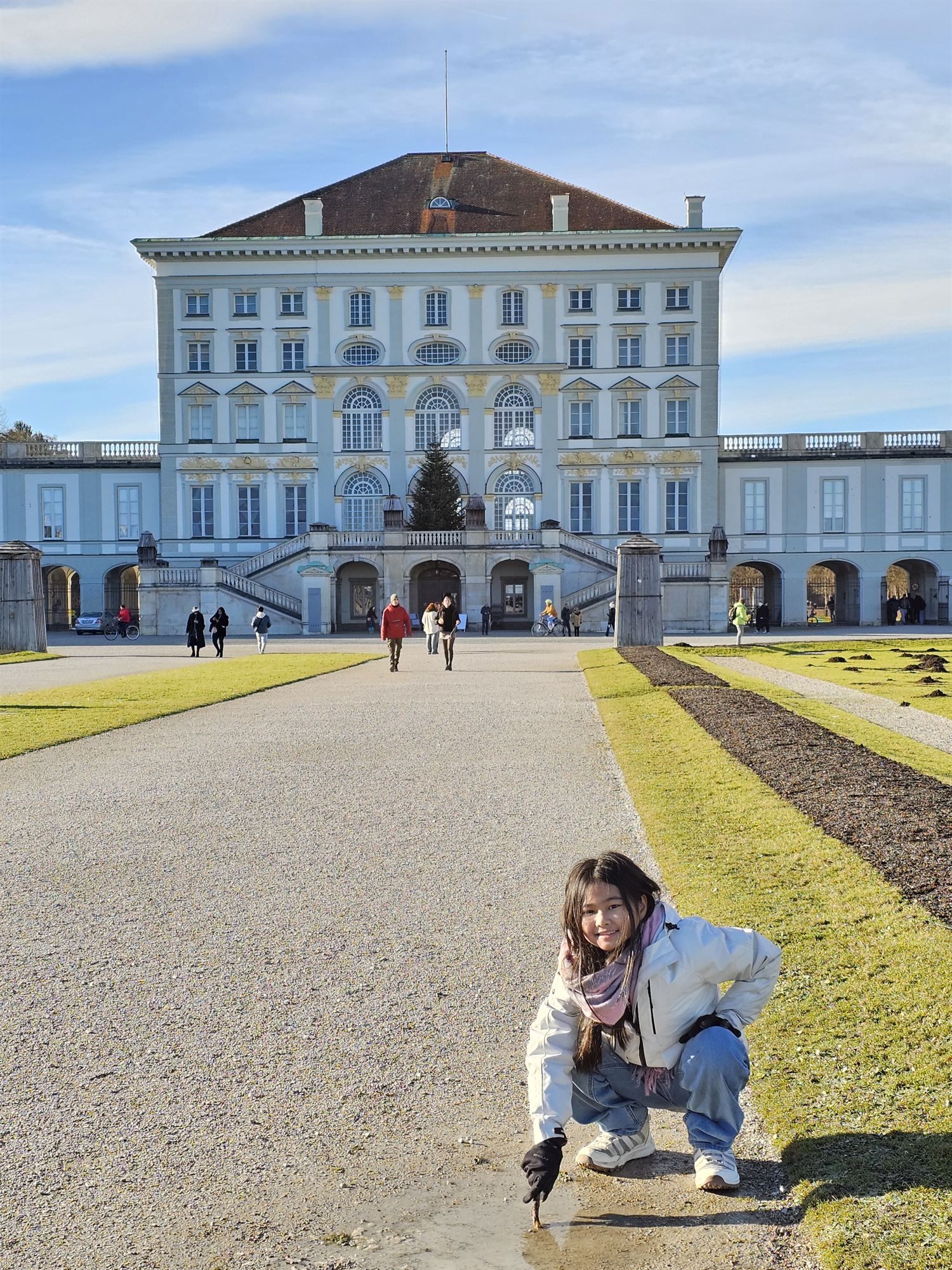 Our daughter crouching in front of Nymphenburg Palace