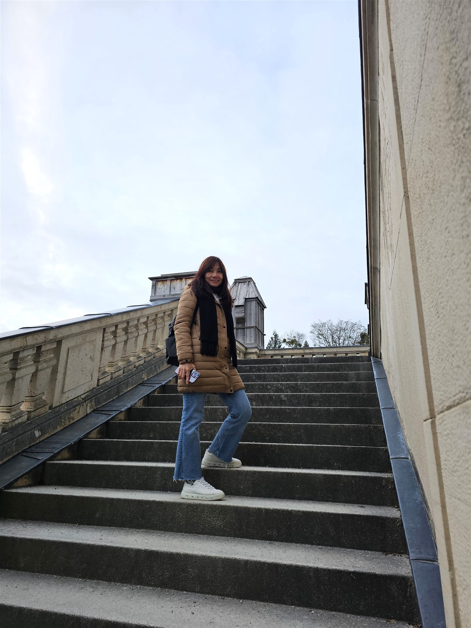 Woman on the stone steps of the palace terrace at Nymphenburg, pale winter sky above