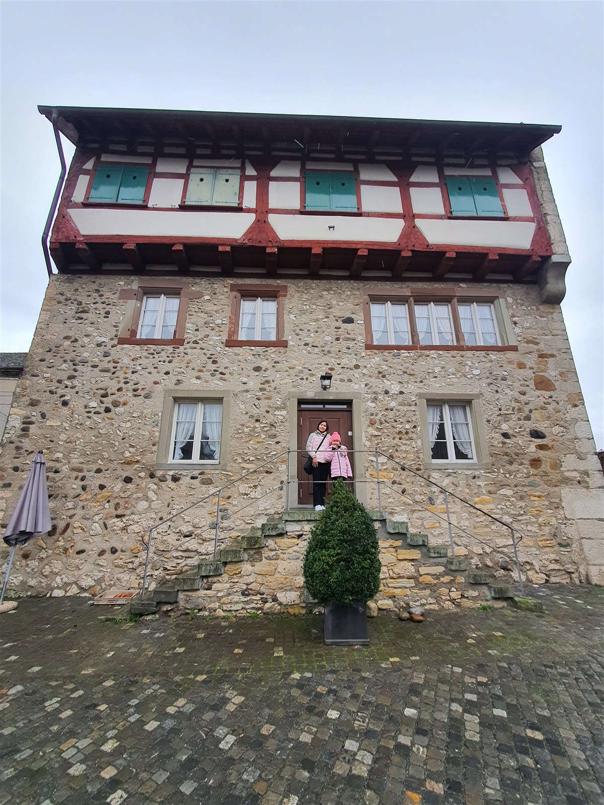 Mother and daughter on the steps of a half-timbered stone house at Laufen Castle