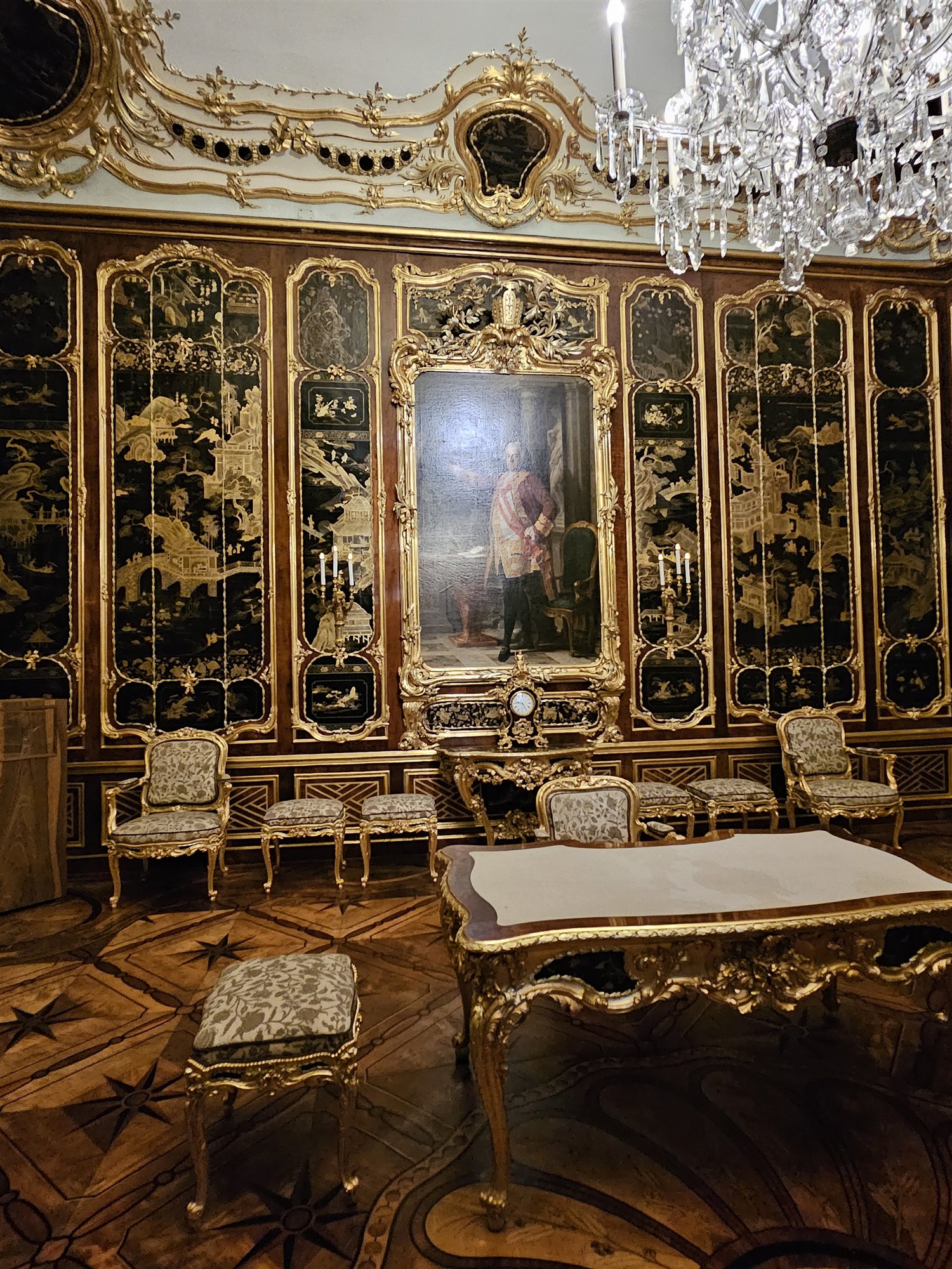 One of Schönbrunn Palace's lacquer-panelled state rooms, gilded portrait frame and crystal chandelier