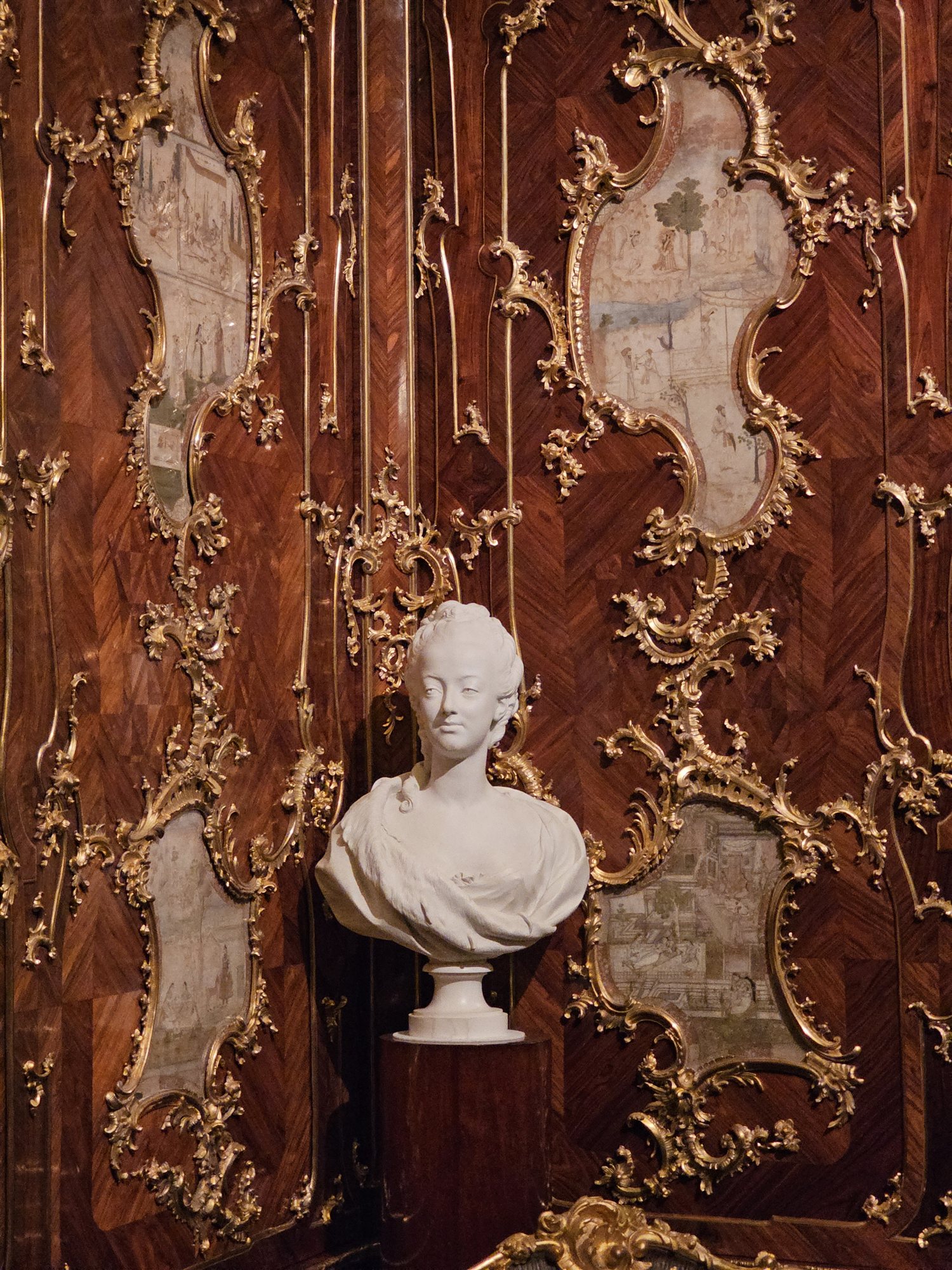 A marble bust displayed against gilded wood panelling inside Schönbrunn Palace