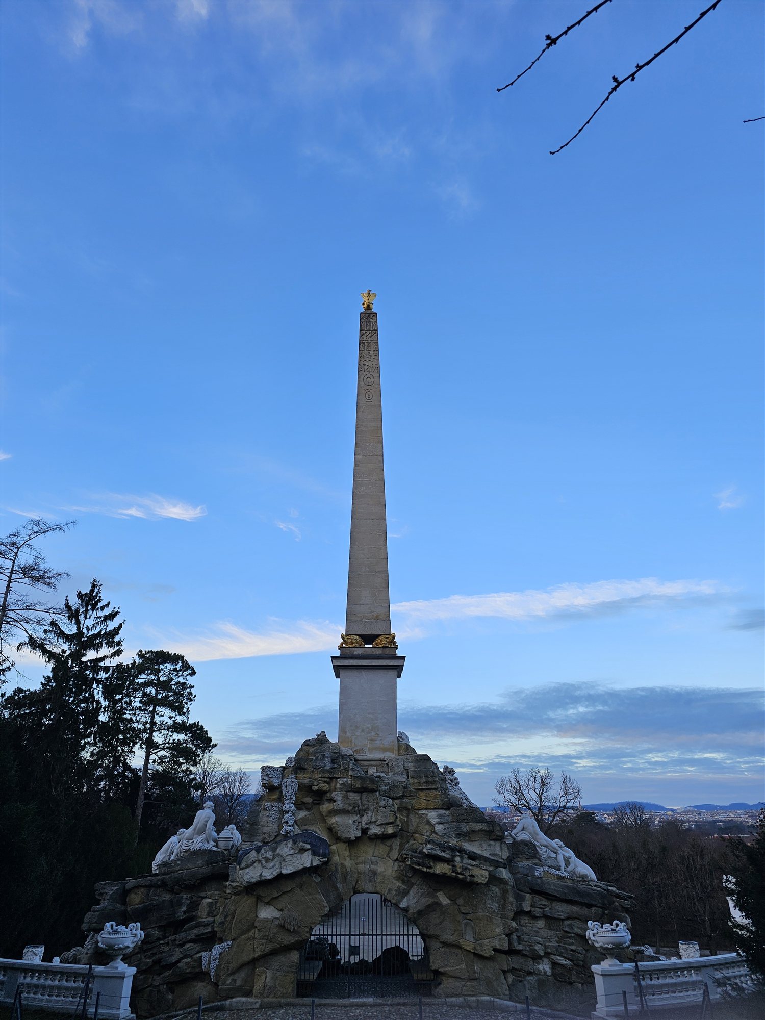 The obelisk fountain in the gardens of Schönbrunn Palace at dusk, a gilded eagle on top