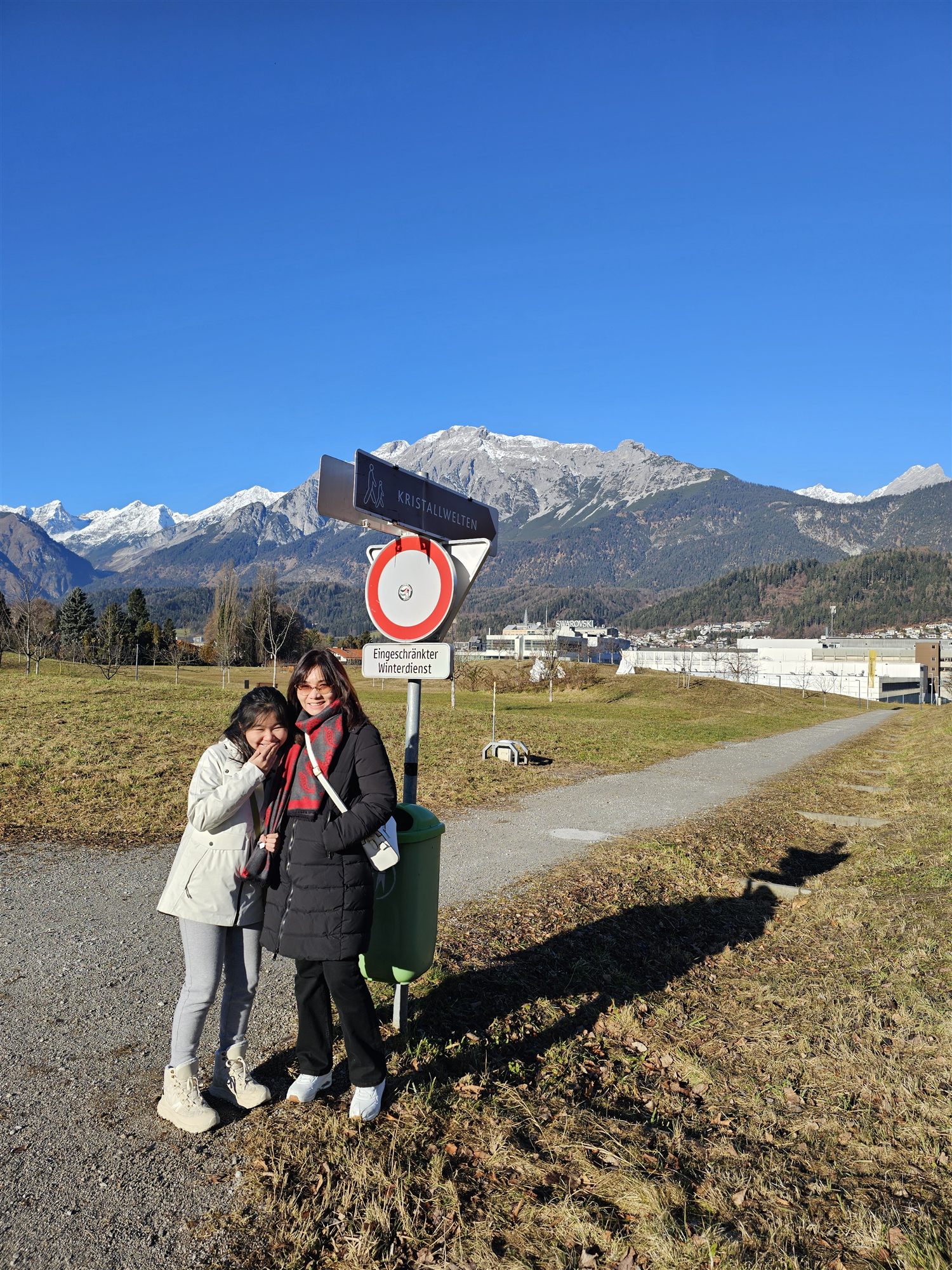 Walking toward Swarovski Crystal Worlds, following the Kristallwelten sign with the Alps behind