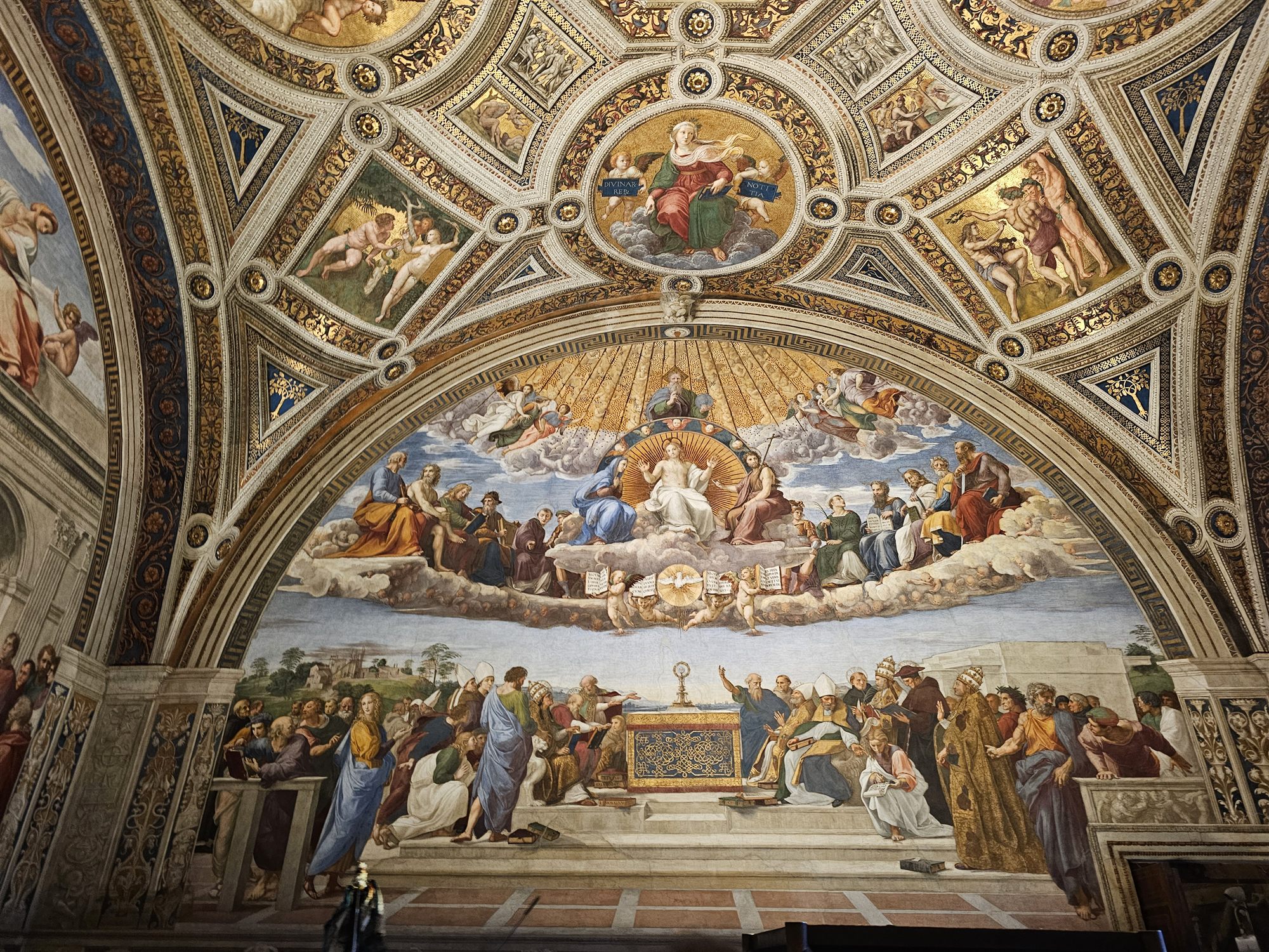 The gilded and painted ceiling of a Raphael Room in the Vatican Museums, with the Disputa-style fresco below