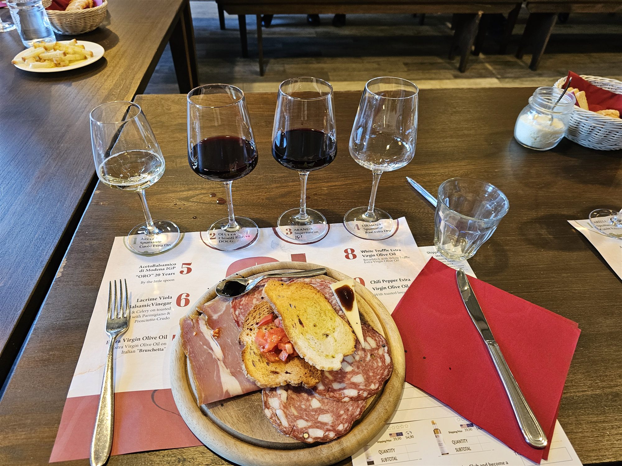 A four-glass wine tasting flight beside a board of bread, cured meats and cheese