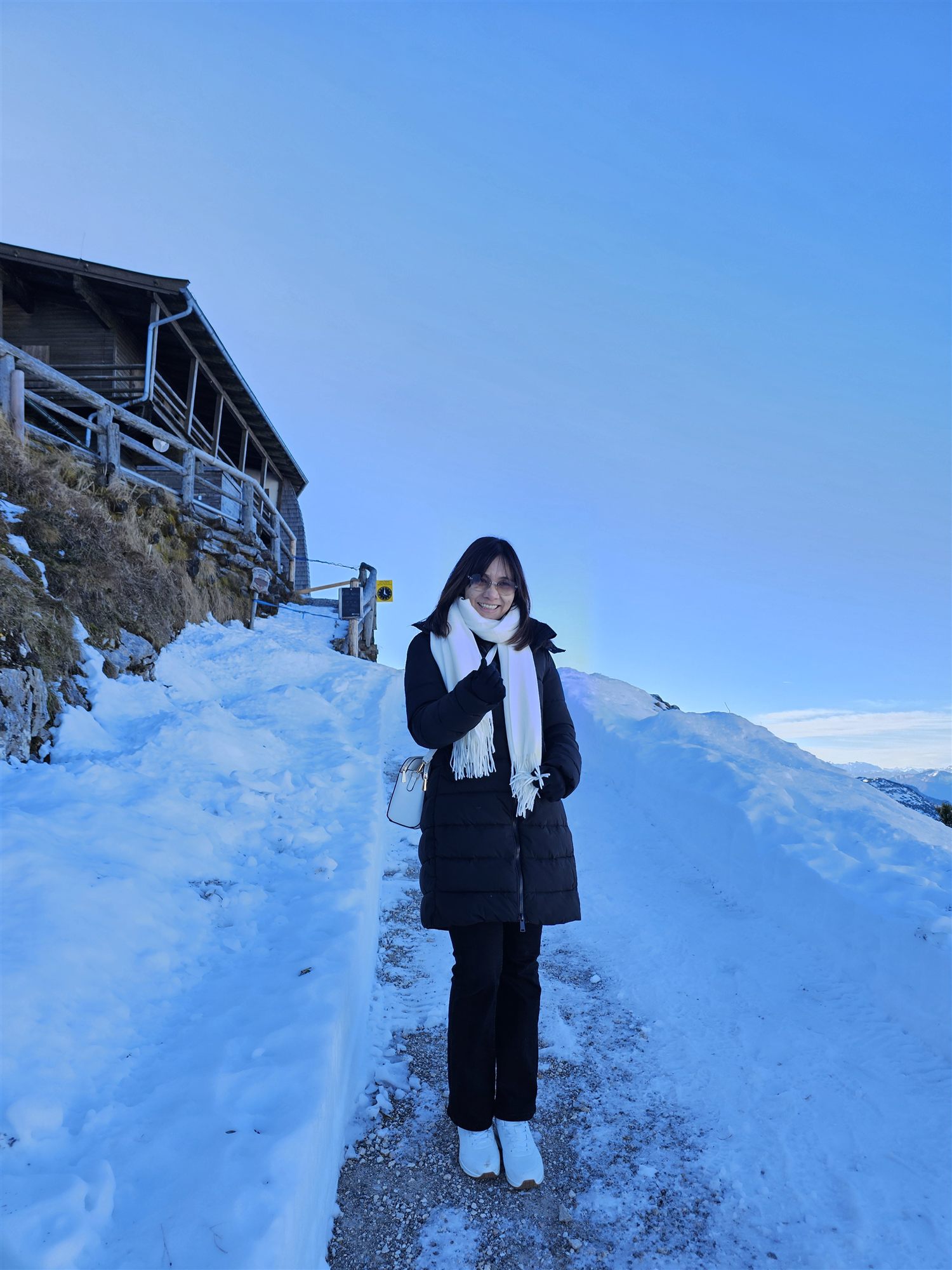 Standing in the snow near a mountain hut at Untersberg's summit, blue sky overhead