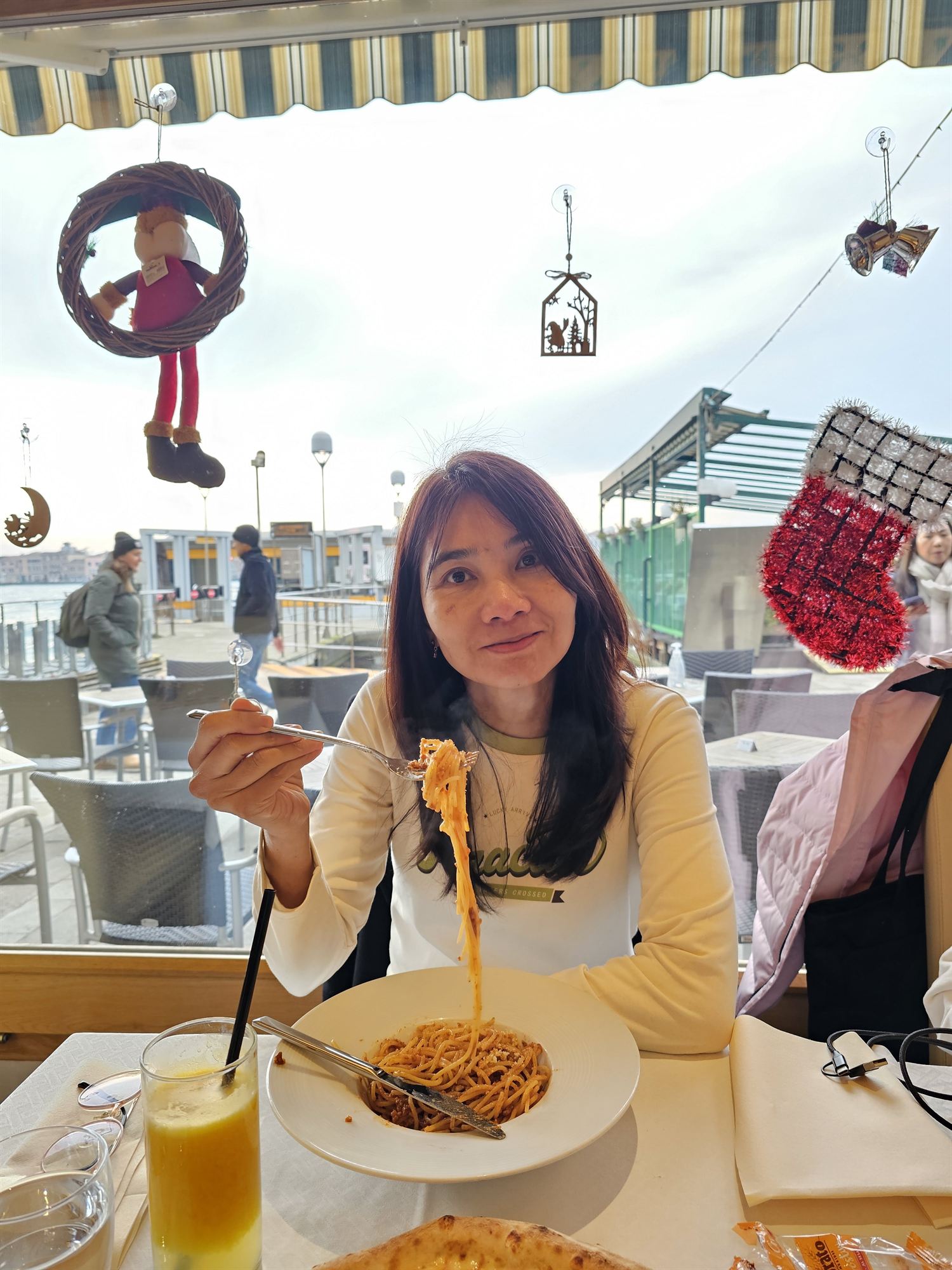 Eating pasta at a waterside restaurant in Venice, Christmas decorations overhead