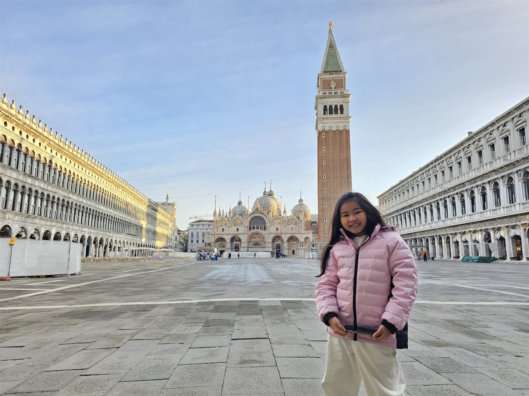 St Mark's Square in the early morning, nearly empty, the basilica and bell tower behind a girl in a pink jacket