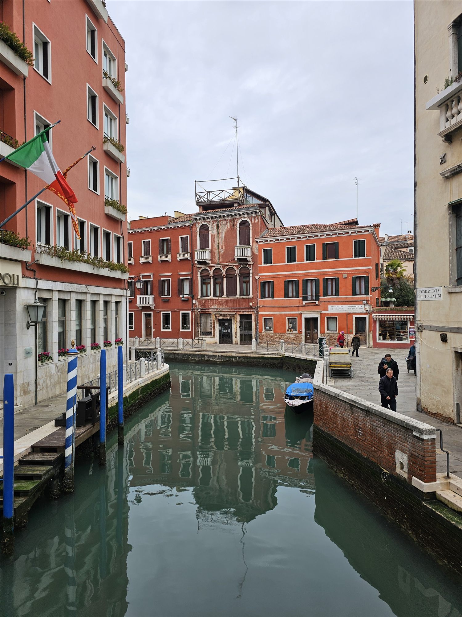 A quiet canal lined with orange palazzos, a moored boat and the Fondamenta dei Tolentini sign