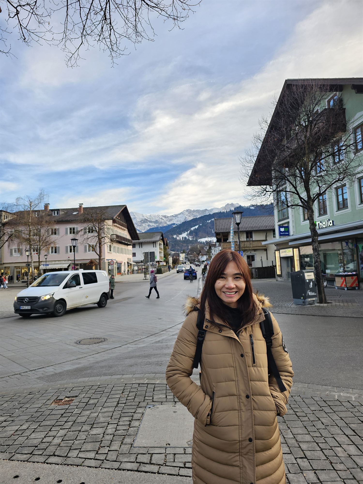 Standing in a town square in Garmisch-Partenkirchen, mountains and shopfronts behind