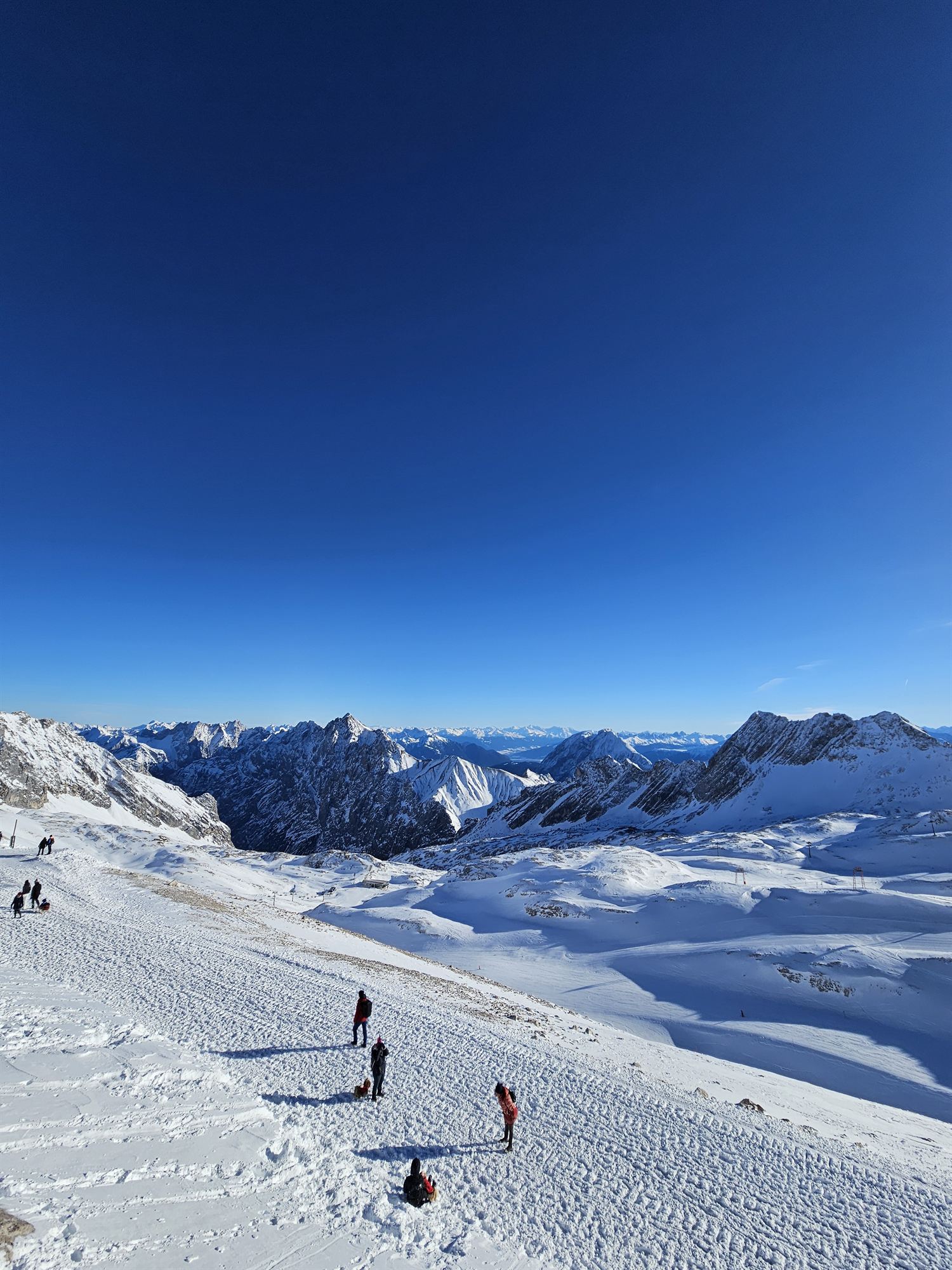 People walking and sledding across the snowy glacier plateau at Zugspitze